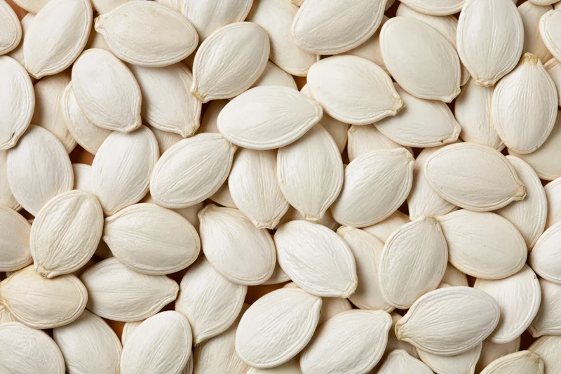 Dried white pumpkin seeds arranged in a flat lay filling the frame