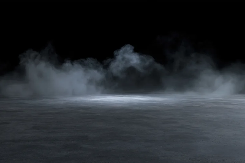 Wisps of smoke rising over a dark concrete floor in a dimly lit space