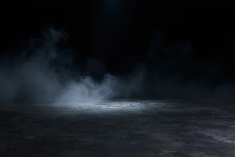 Wisps of smoke rising over a dark concrete floor under a spotlight