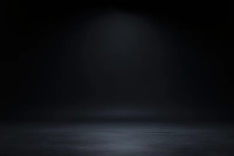 Dark studio space with spotlight on seamless black backdrop and reflective floor