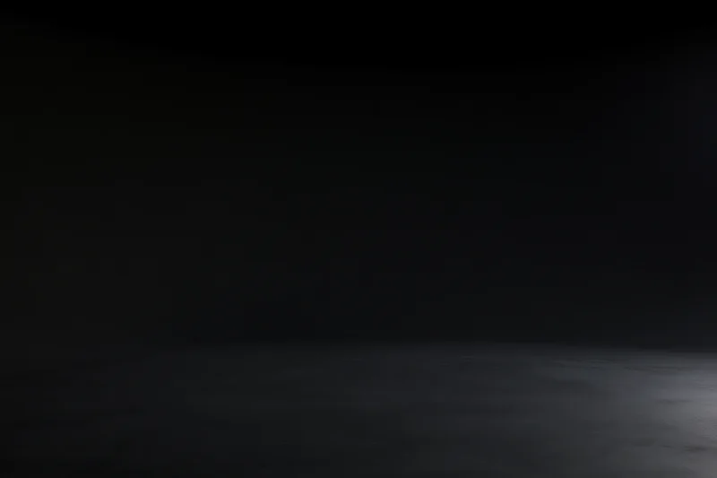 Seamless black studio backdrop with floor meeting wall in dark empty space