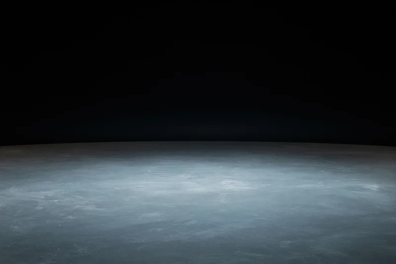 Dark studio space with concrete floor lit by soft ambient light