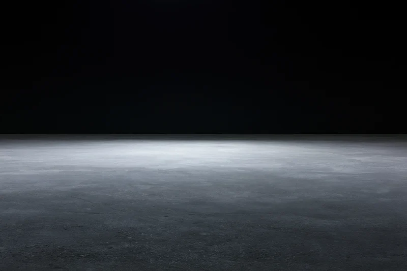 Dark studio interior with spotlight on concrete floor, empty space for display