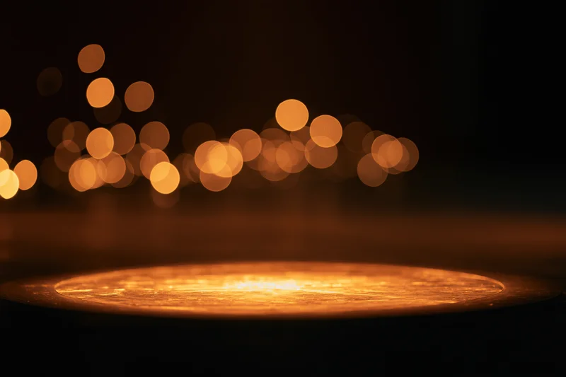 Warm amber spotlight pool on dark studio stage floor with bokeh lights in background