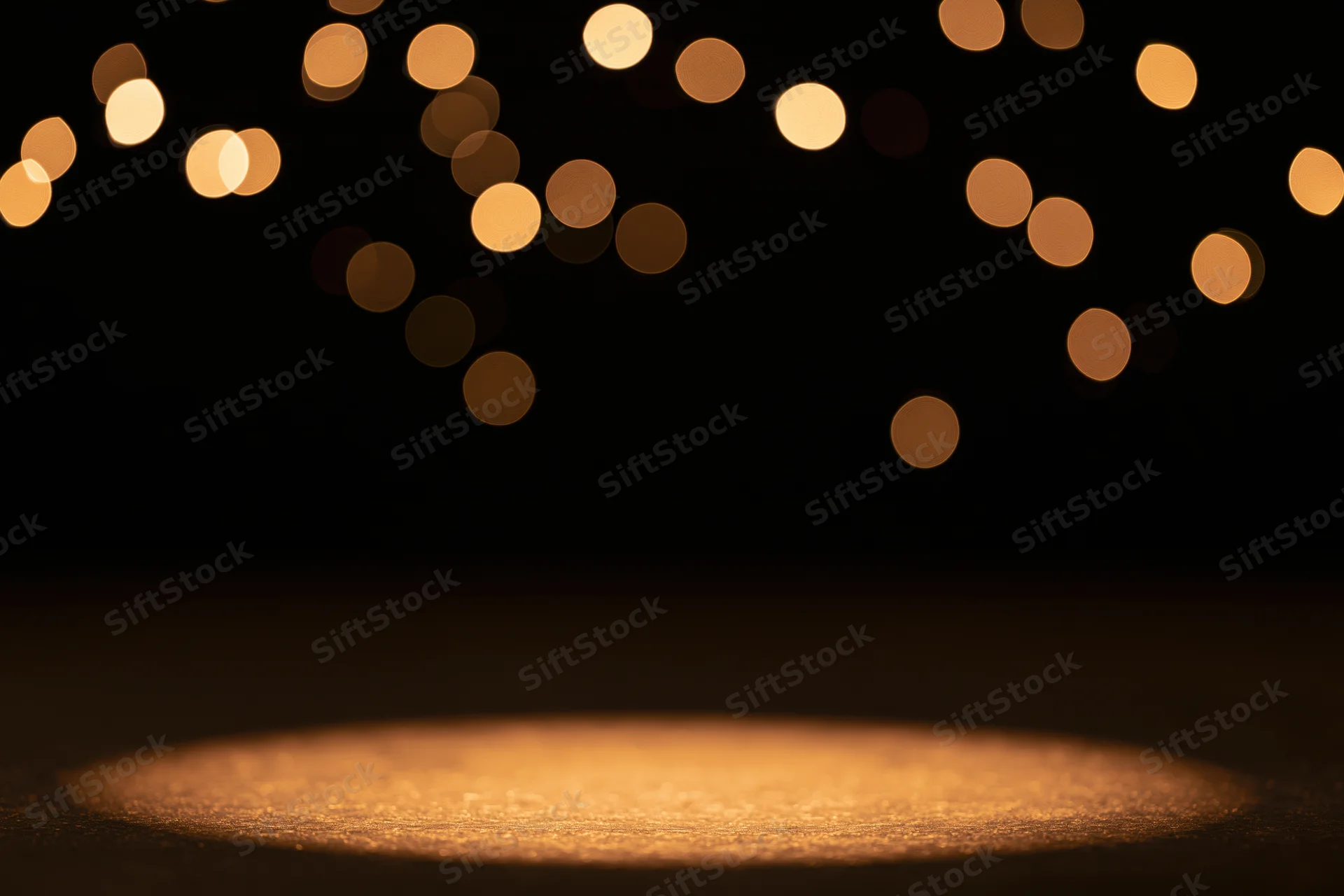 Warm amber spotlight pool on dark studio stage floor with bokeh lights above
