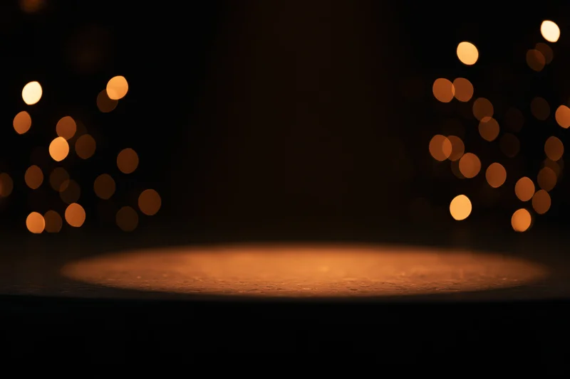Warm amber spotlight on empty dark studio stage with bokeh lights in background