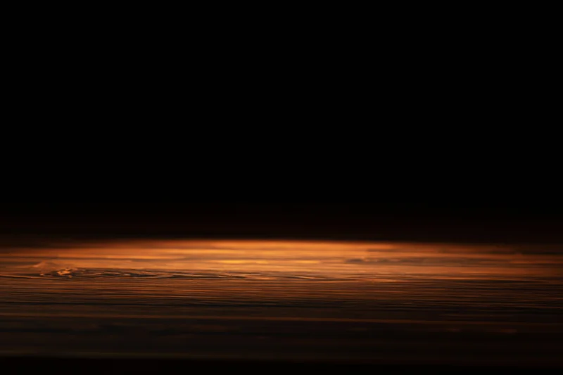 Dark wooden surface illuminated by a narrow spotlight with warm orange glow