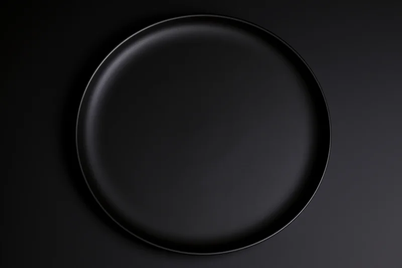 Matte black ceramic dinner plate centered on dark surface