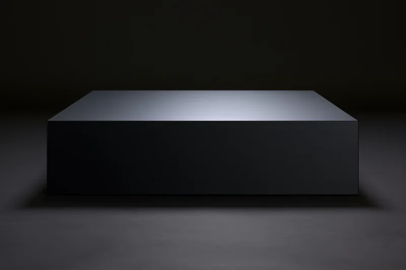 Matte black rectangular pedestal on dark floor under spotlight