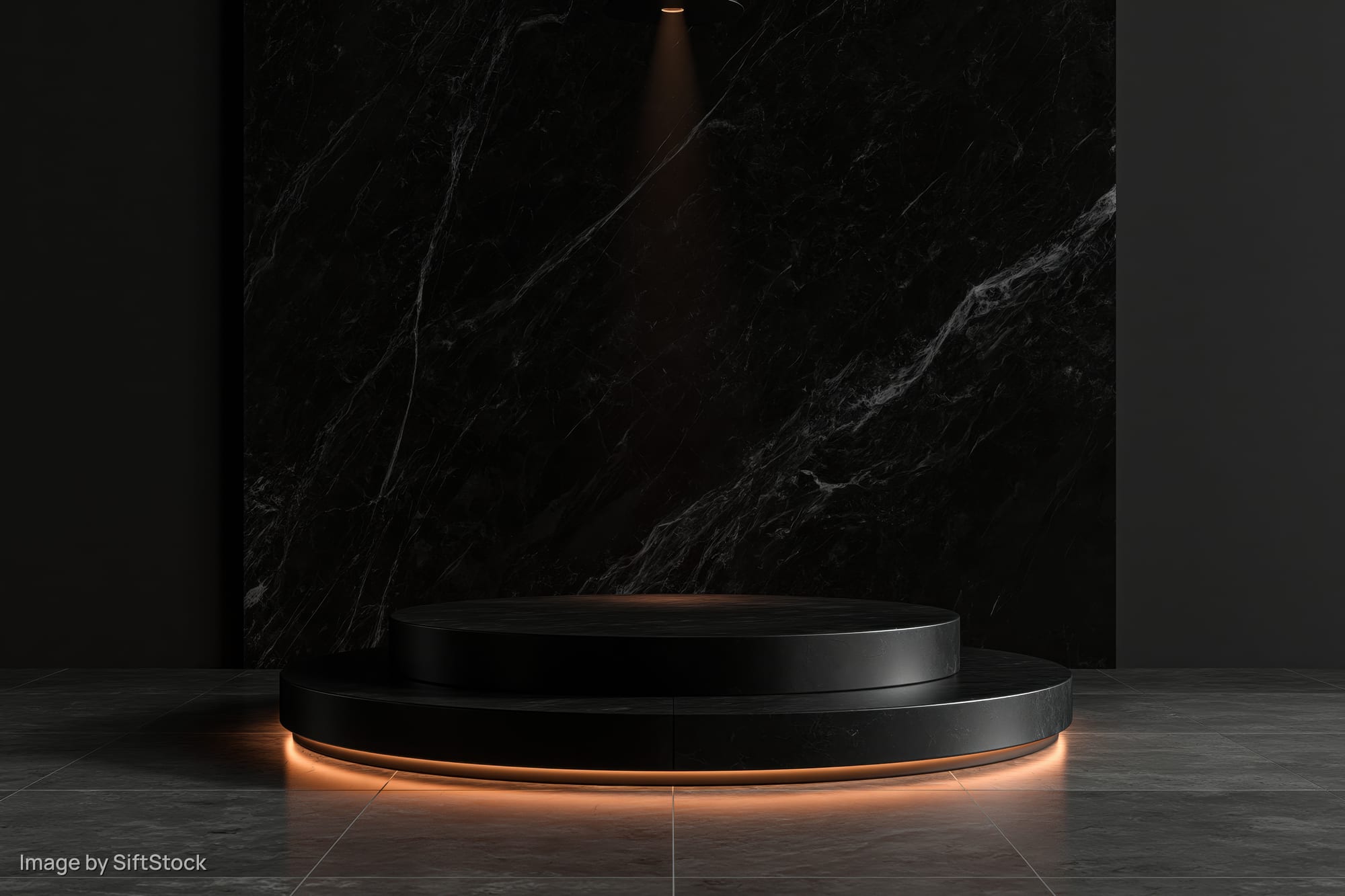 Two-tiered black stone pedestal with warm lighting in a dark showroom space