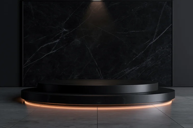 Two-tiered black stone pedestal with warm glow lighting in a minimalist showroom