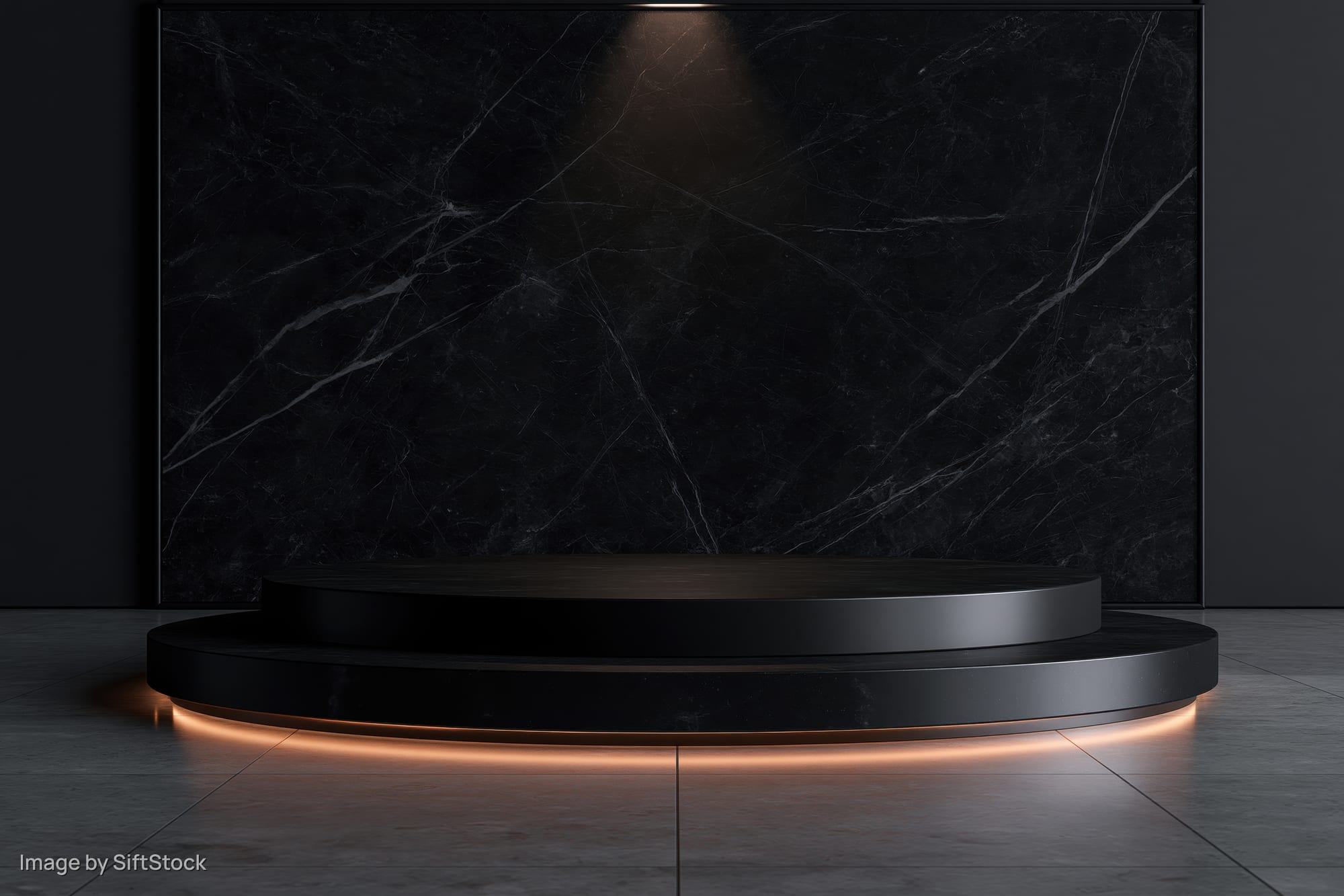 Two-tiered black stone pedestal with warm glow lighting in a minimalist showroom