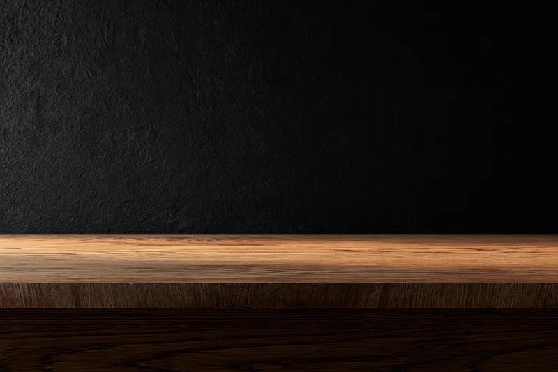 Empty wooden tabletop surface against dark textured plaster wall