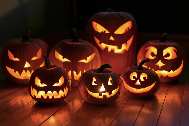 Carved jack-o-lanterns glowing on a wooden floor