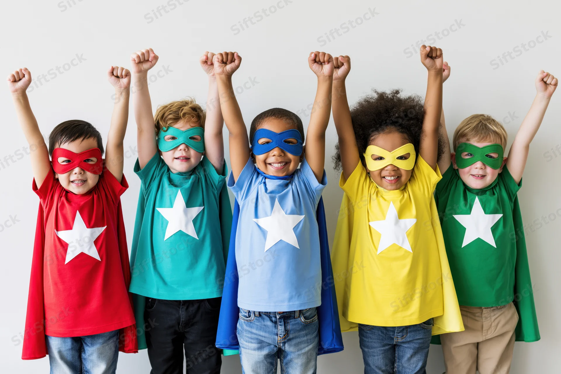 Five children in superhero costumes with raised fists standing in a row