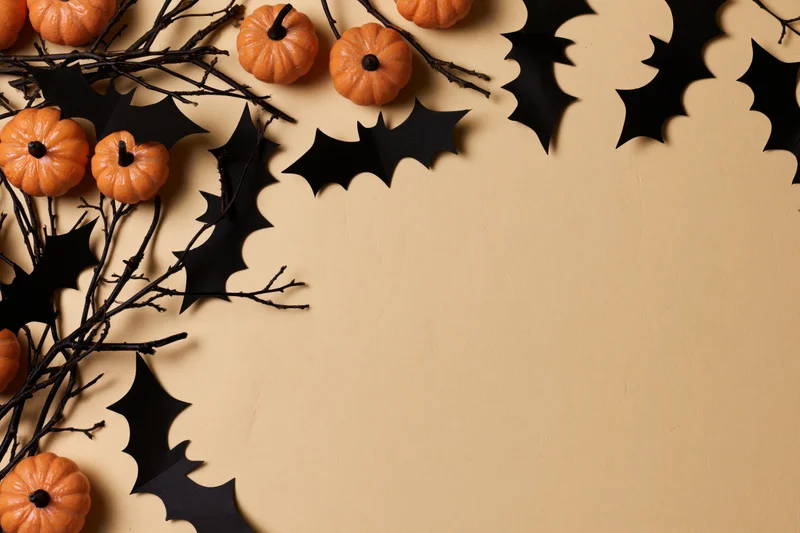 Halloween decoration arrangement with small orange pumpkins, black paper bats, and branches on beige surface
