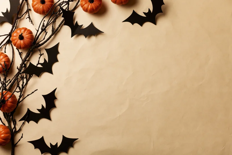 Halloween decoration flat lay with pumpkins and bat cutouts on textured paper background