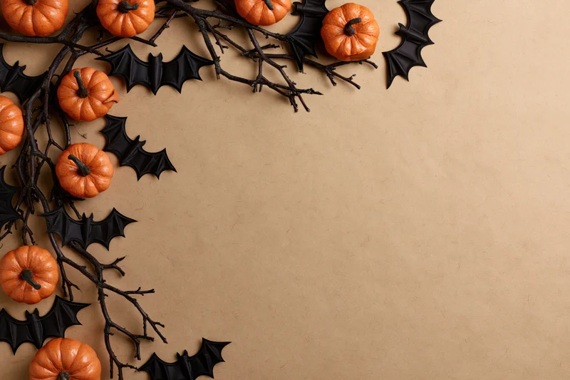 Halloween decoration arrangement with pumpkins and bats on branches along the left side of a brown paper background