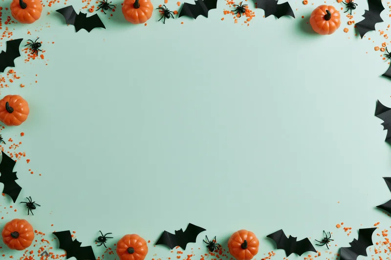 Halloween decorations arranged as a border frame on a mint background with copyspace
