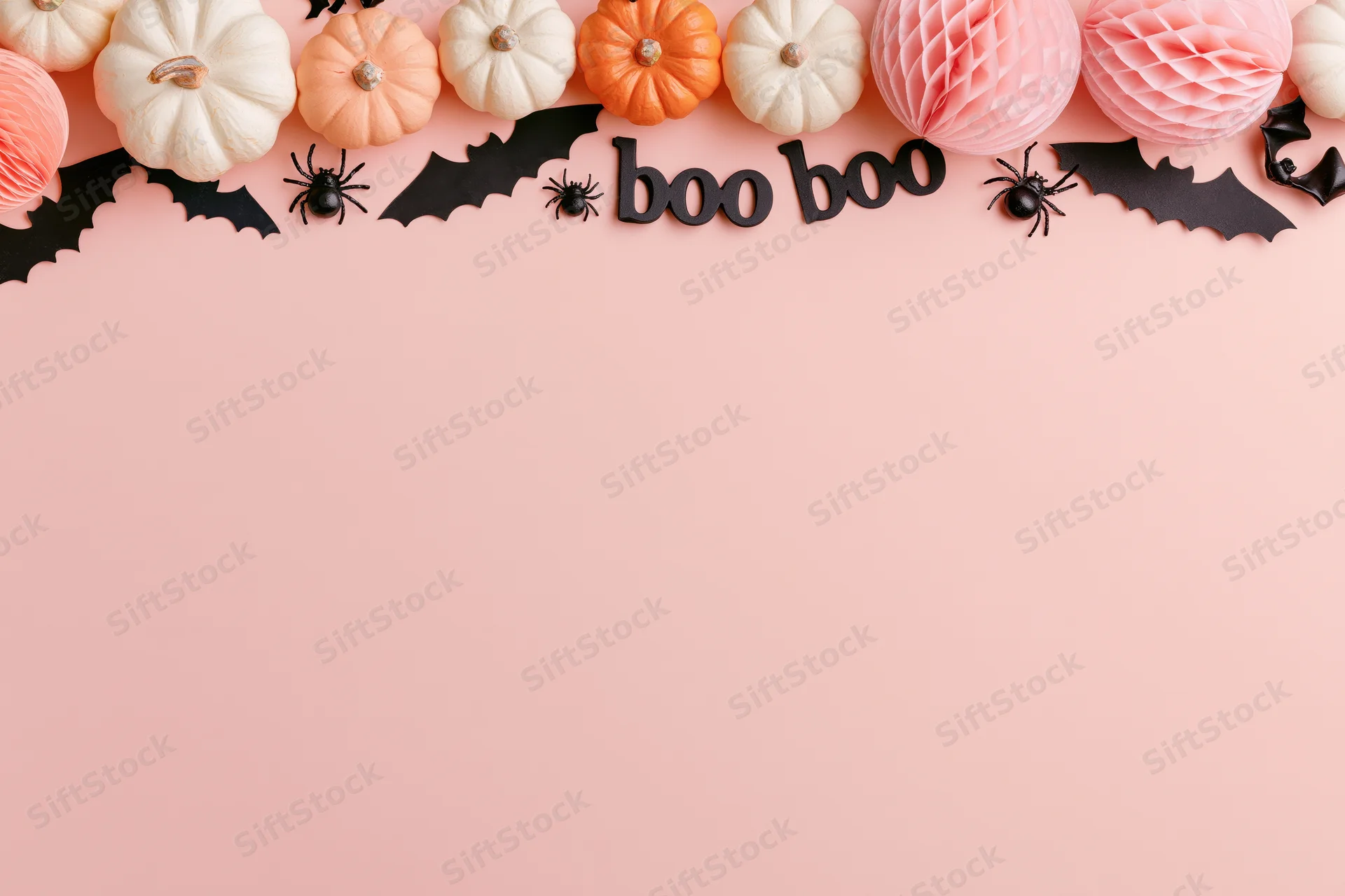Halloween decorations arranged along the top edge on a pink surface with copyspace below