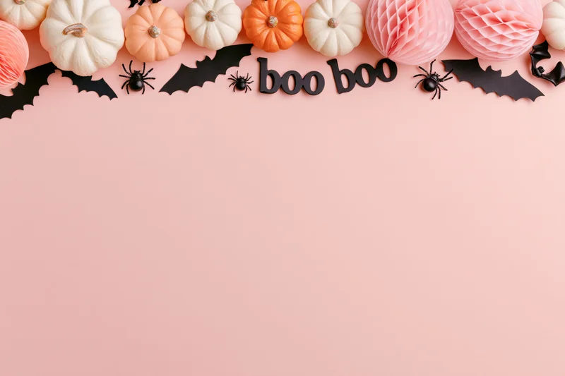 Halloween decorations arranged along the top edge on a pink surface with copyspace below