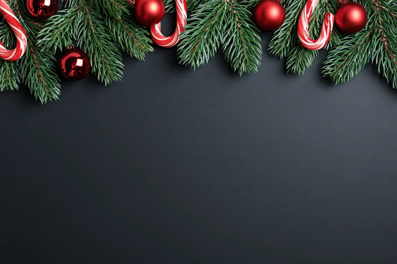 Pine branches with red ornaments and candy canes arranged along top edge of dark surface