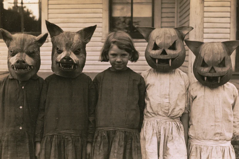 Five children in handmade halloween masks standing on a porch in front of a house