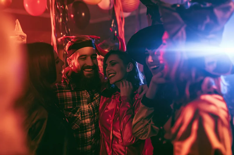 Friends in halloween costumes dancing together at an indoor party