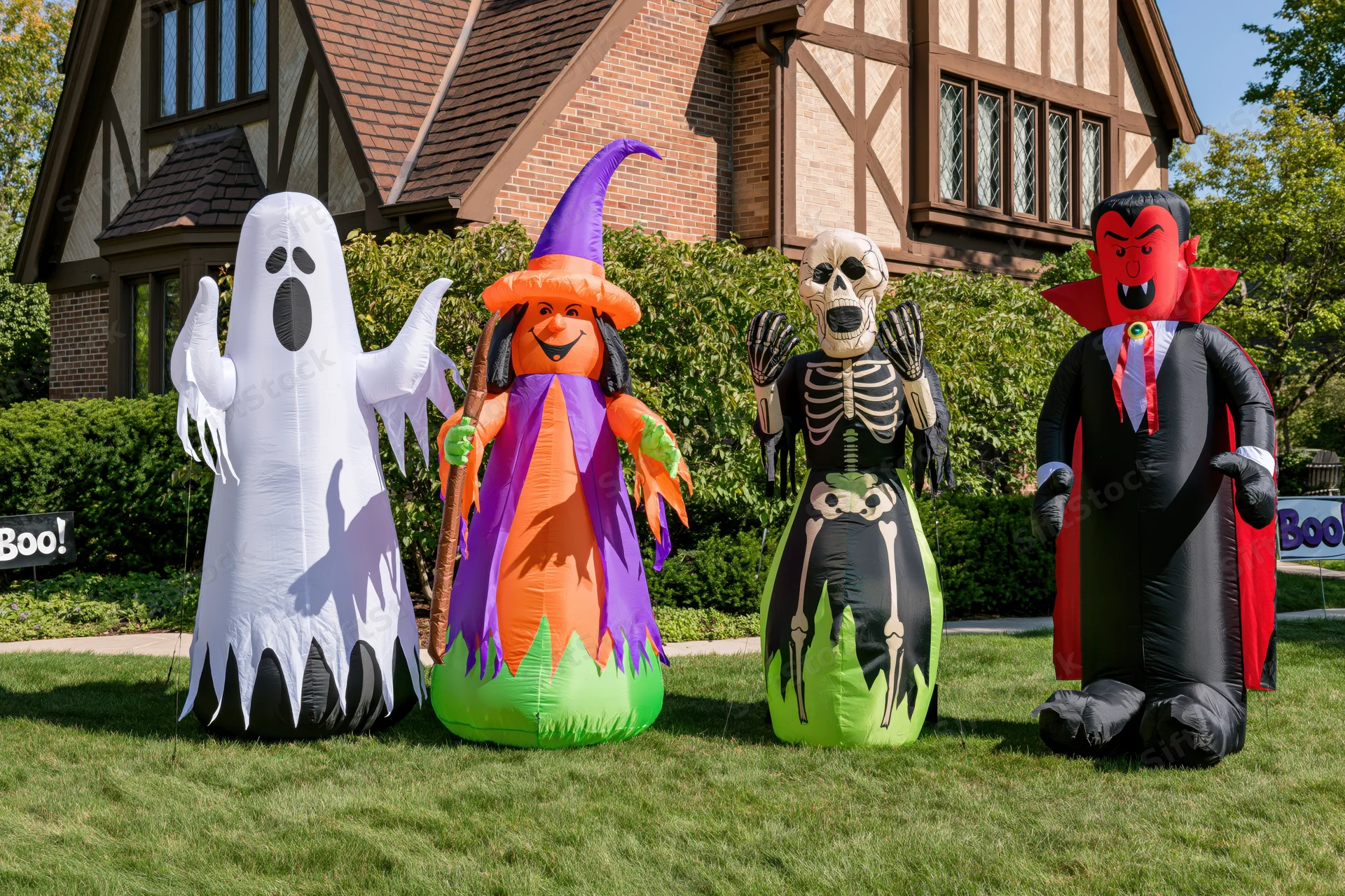Four inflatable halloween characters lined up on a front lawn in front of a house