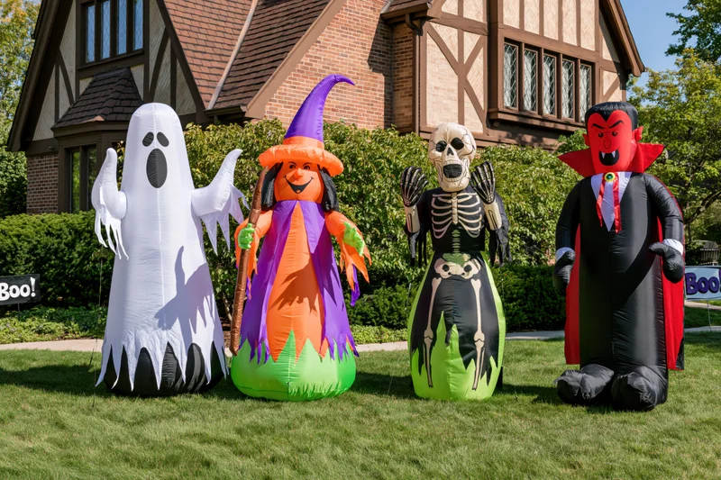 Four inflatable halloween characters lined up on a front lawn in front of a house