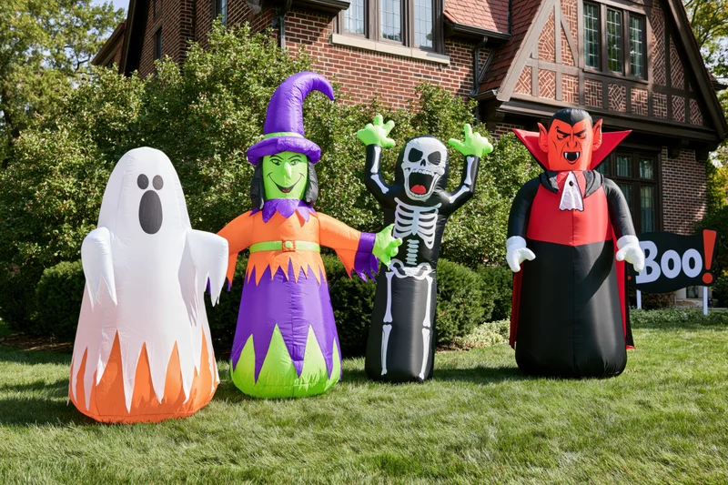 Inflatable halloween characters lined up on a grassy lawn in front of a brick house