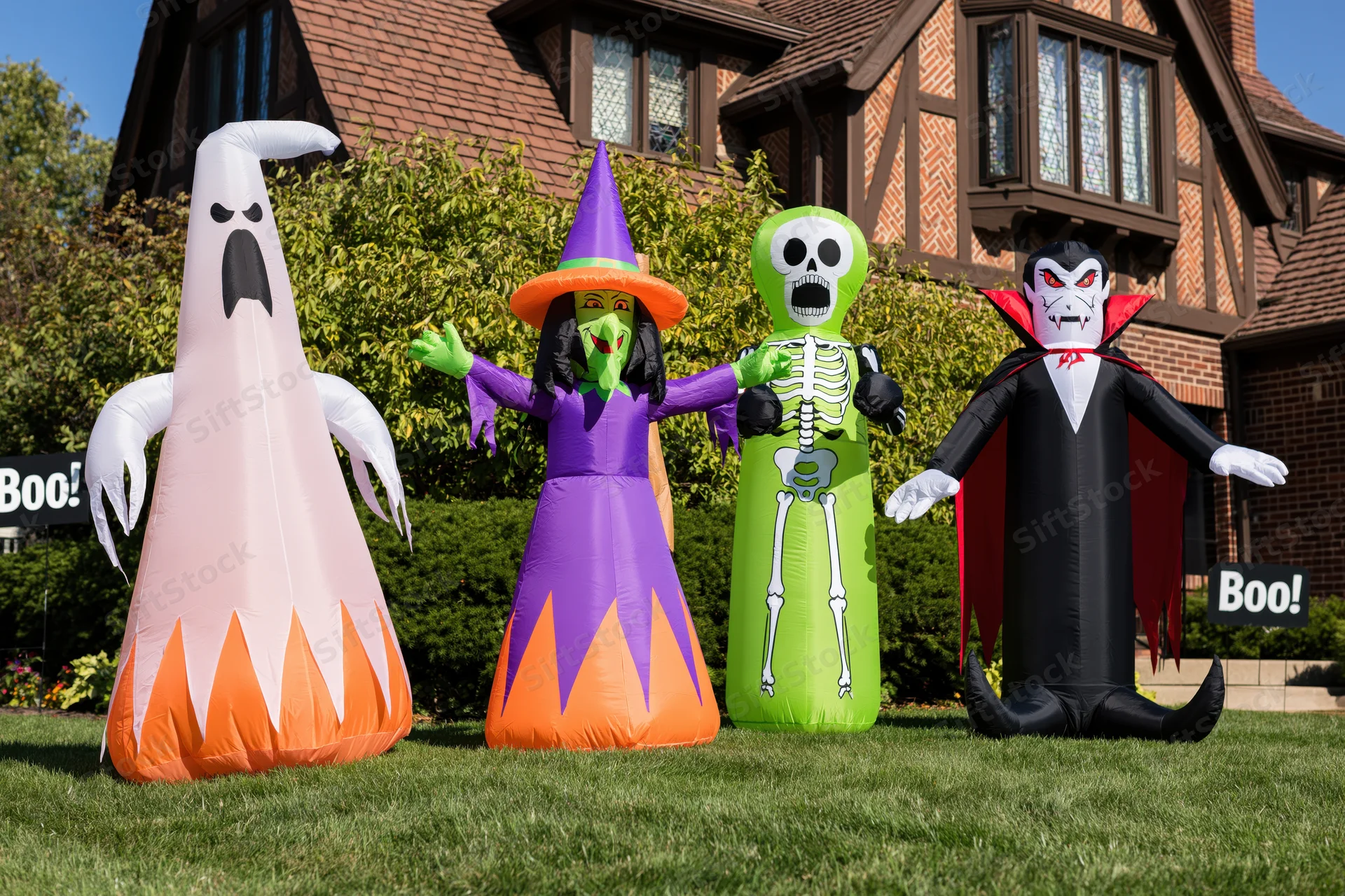 Four inflatable halloween characters standing on a front lawn in front of a house