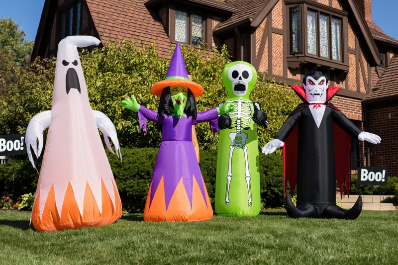 Four inflatable halloween characters standing on a front lawn in front of a house