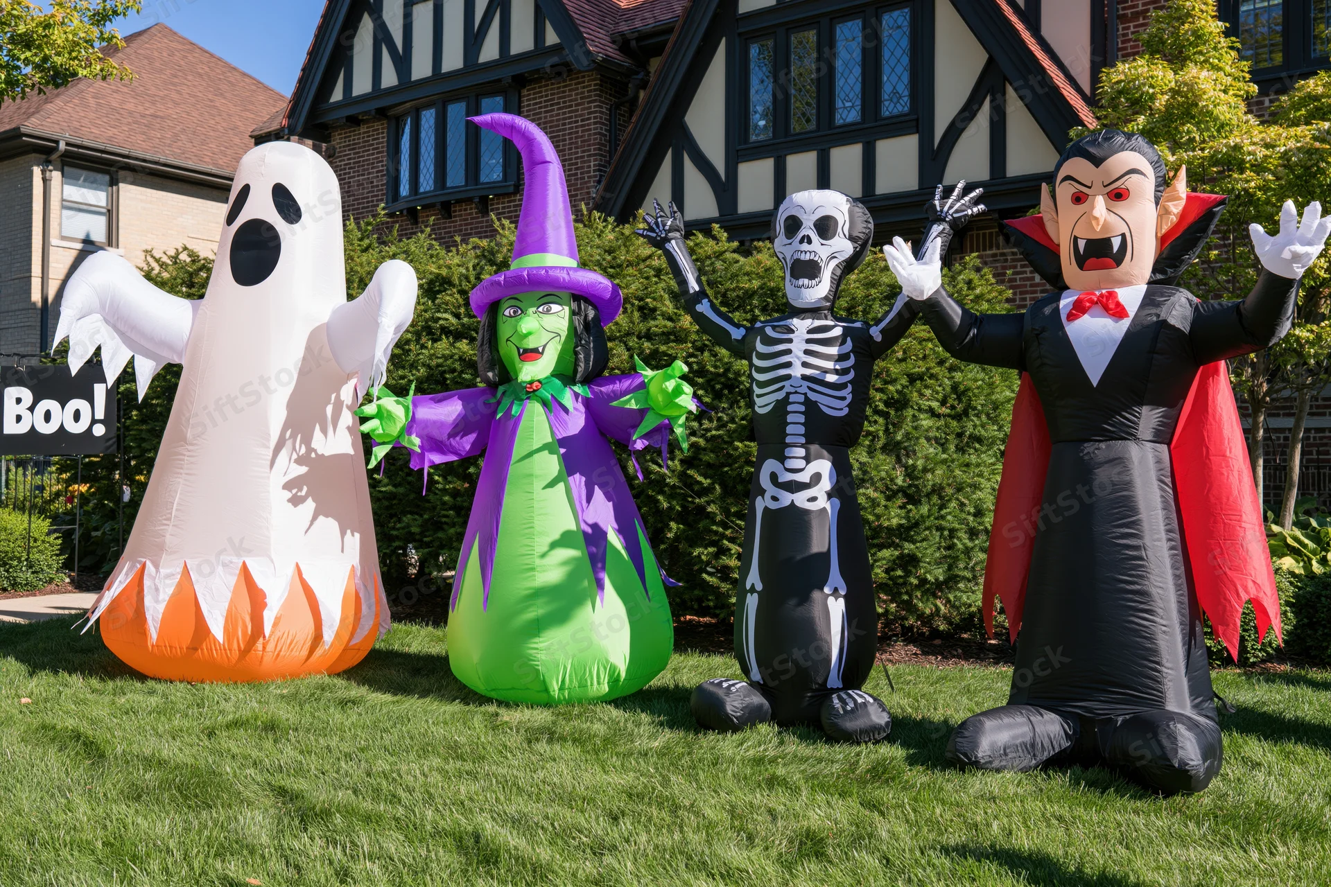 Four inflatable halloween characters lined up on a suburban lawn in front of a house