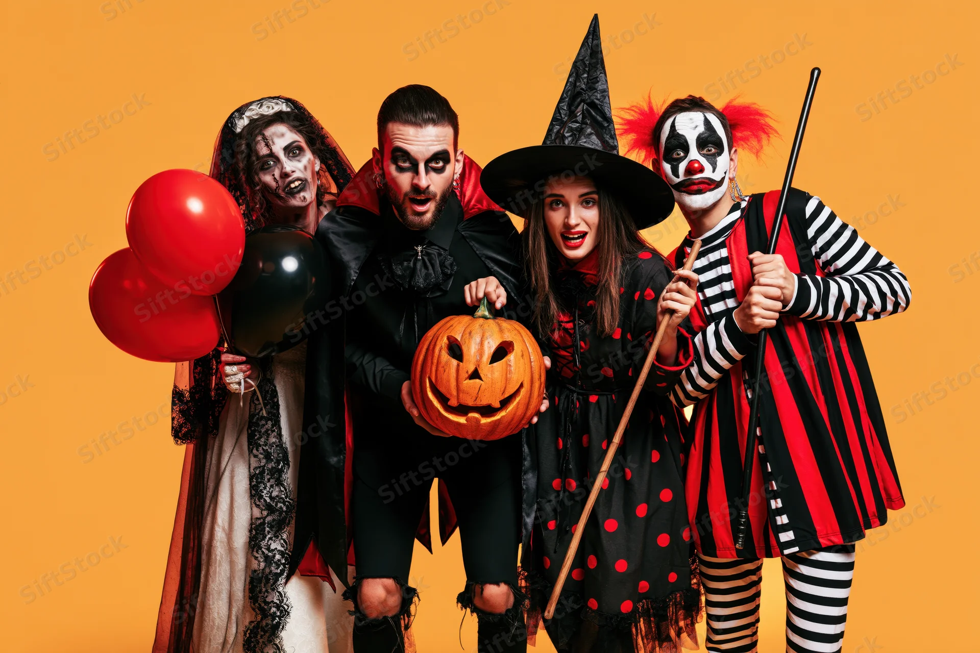 Four young adults in halloween costumes posing together against orange background