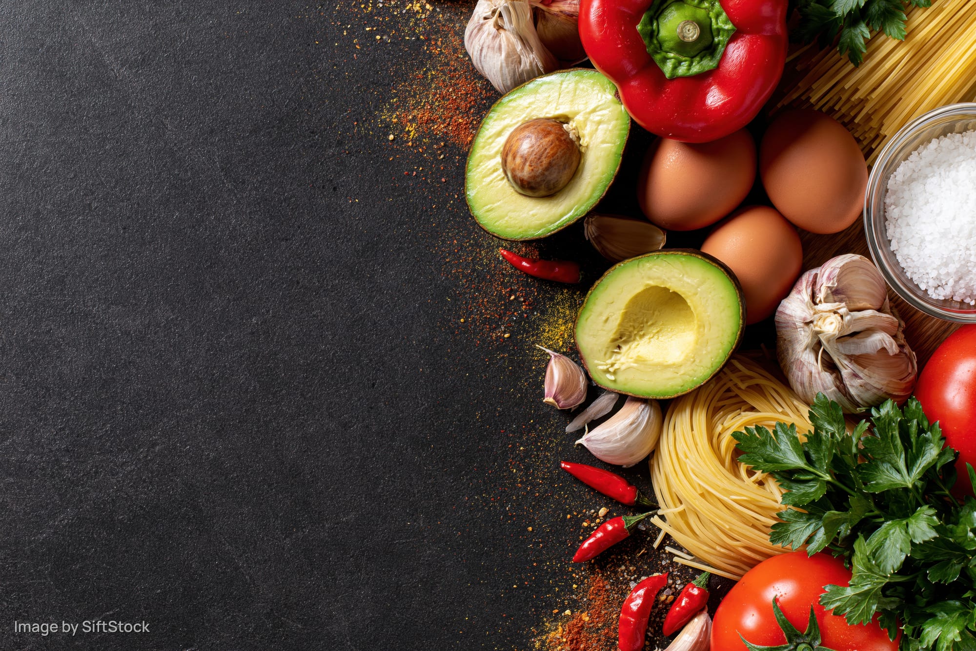 Fresh cooking ingredients arranged along the right edge on a dark surface