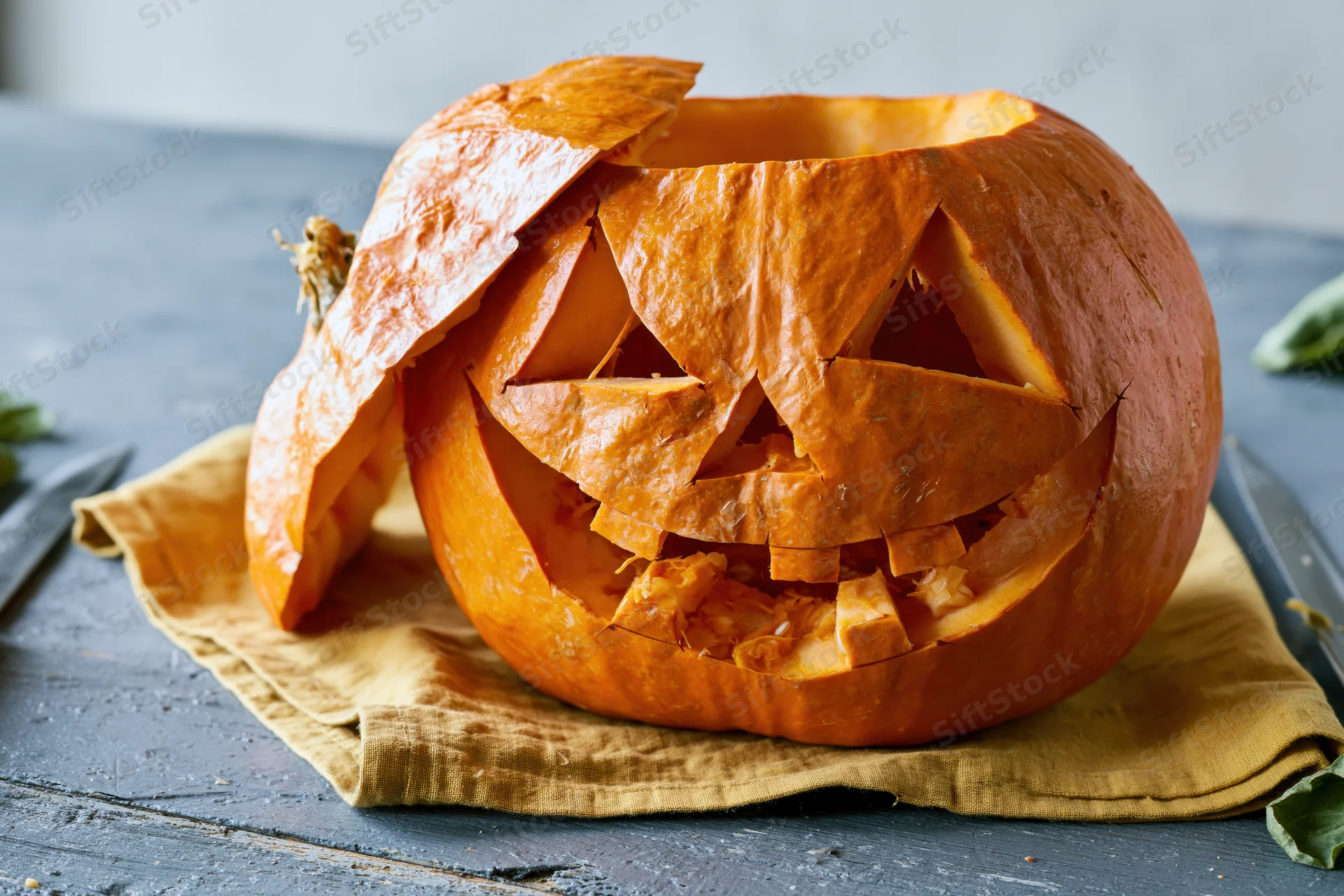 Carved pumpkin with jagged triangular face on a cloth-covered table