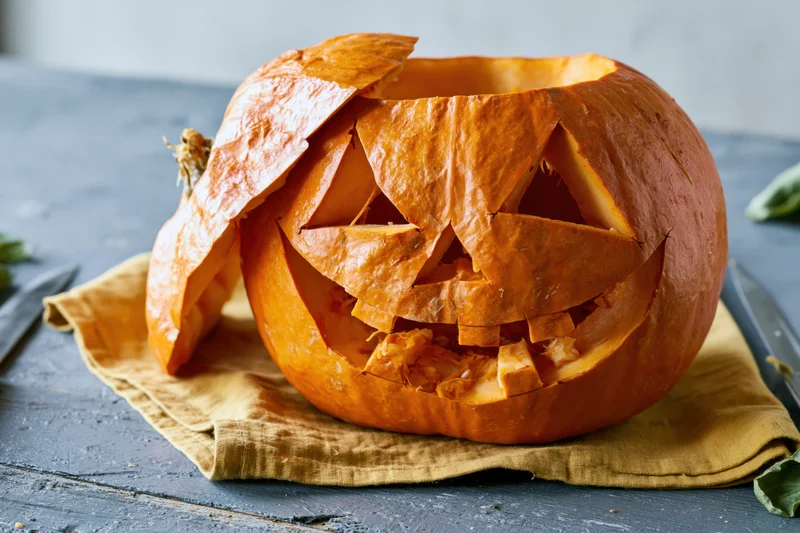 Carved pumpkin with jagged triangular face on a cloth-covered table