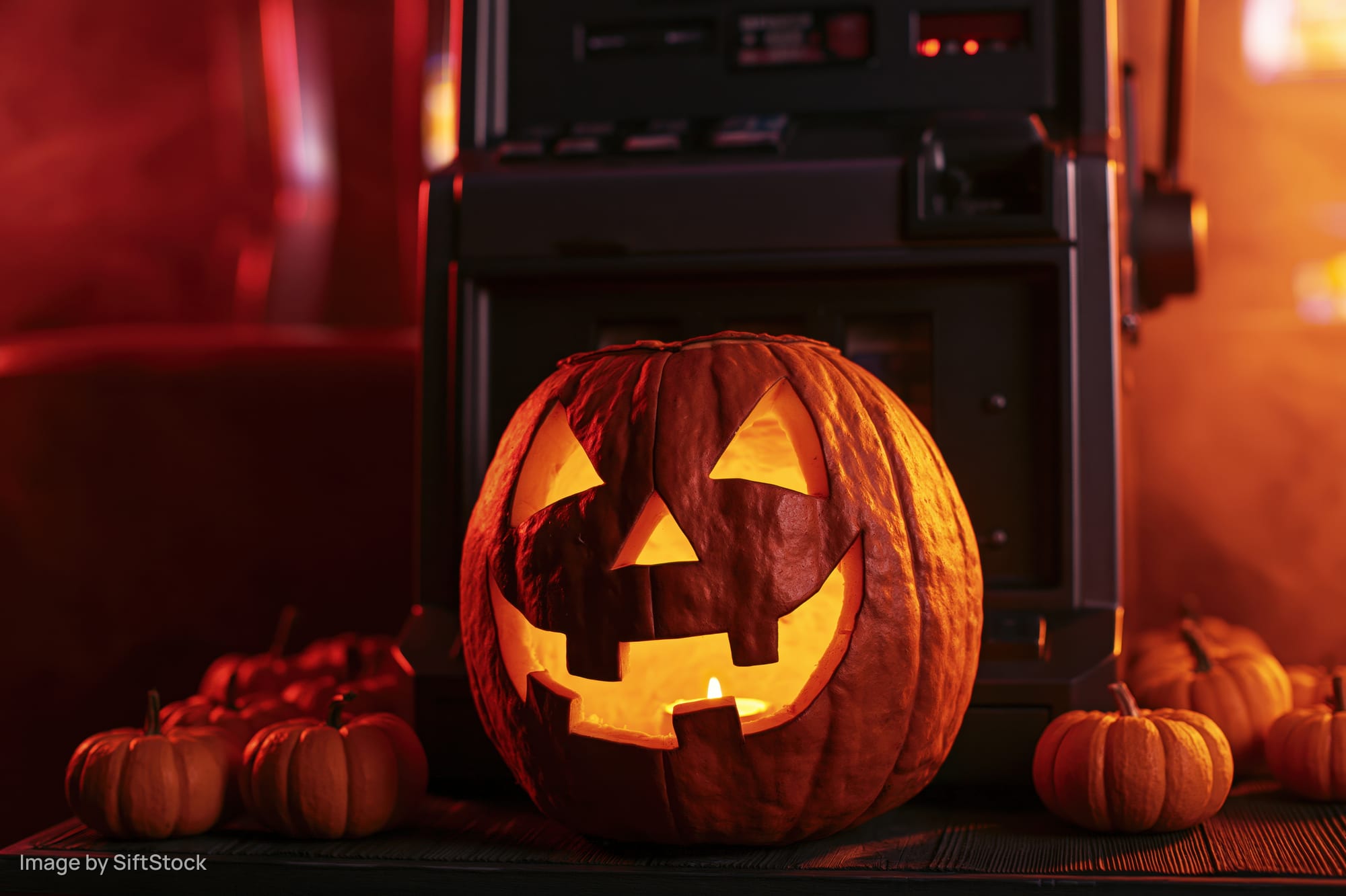 Glowing carved pumpkin with candlelight on table in front of slot machine at casino
