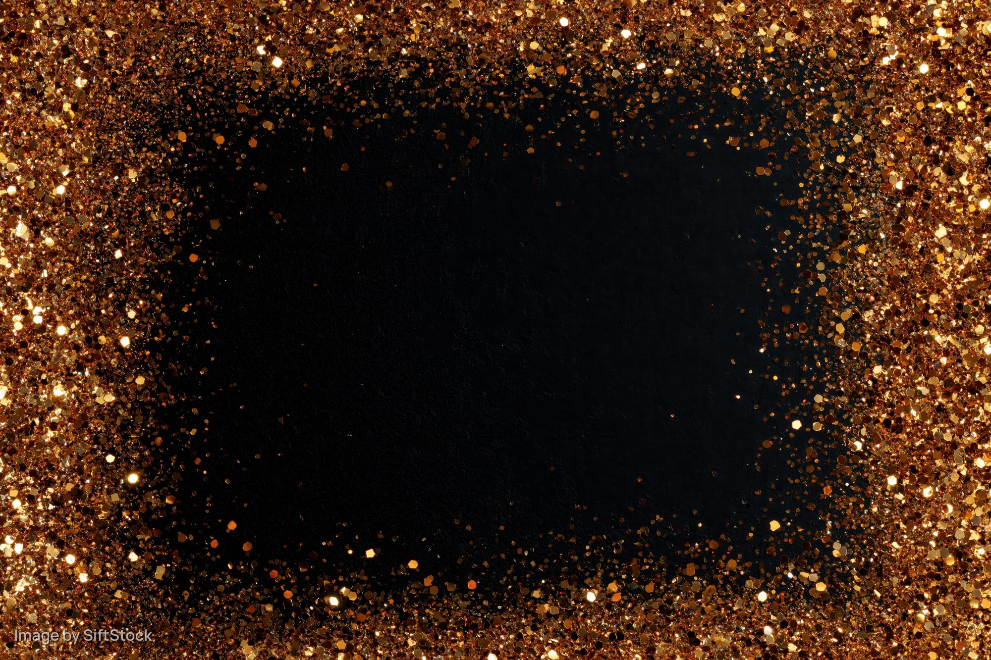 Gold glitter particles forming a circular frame around a dark center, creating a festive border with copyspace in the middle