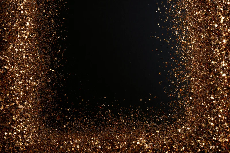 Gold glitter particles forming a sparkling frame around a dark center with copyspace