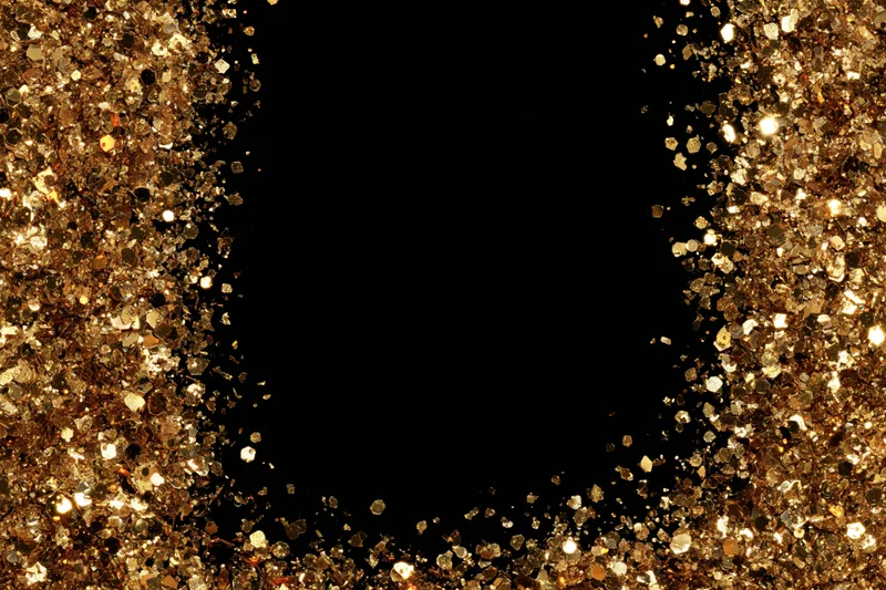 Gold glitter particles forming a sparkling frame around a black copyspace