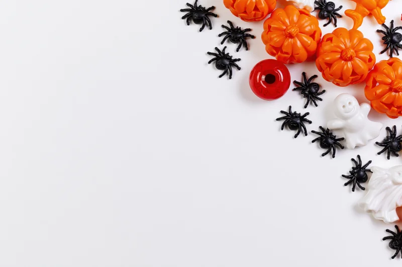 Halloween decorations arranged along the right edge of a white surface with copyspace on the left