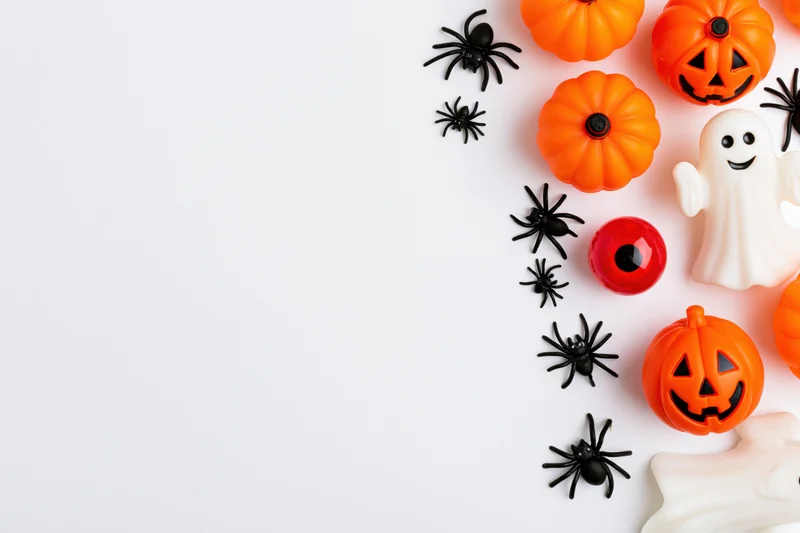 Halloween decorations arranged along the right edge of a white surface with copyspace on the left