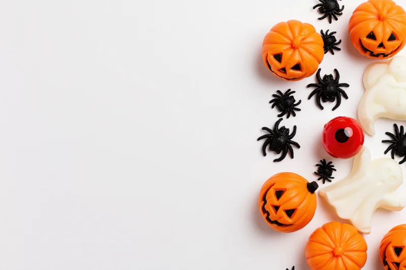 Halloween decorations arranged along the right edge of a white surface with copyspace on the left