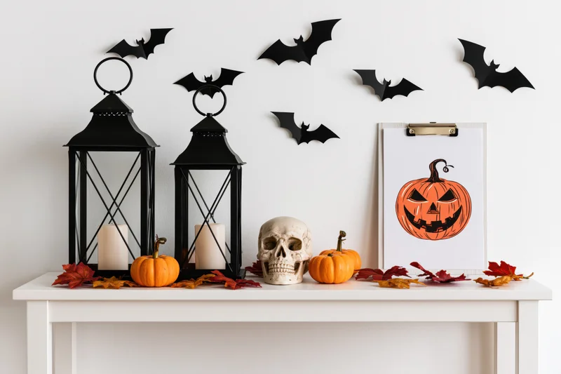Halloween decorations arranged on a white shelf with pumpkins, skull, lanterns and bats