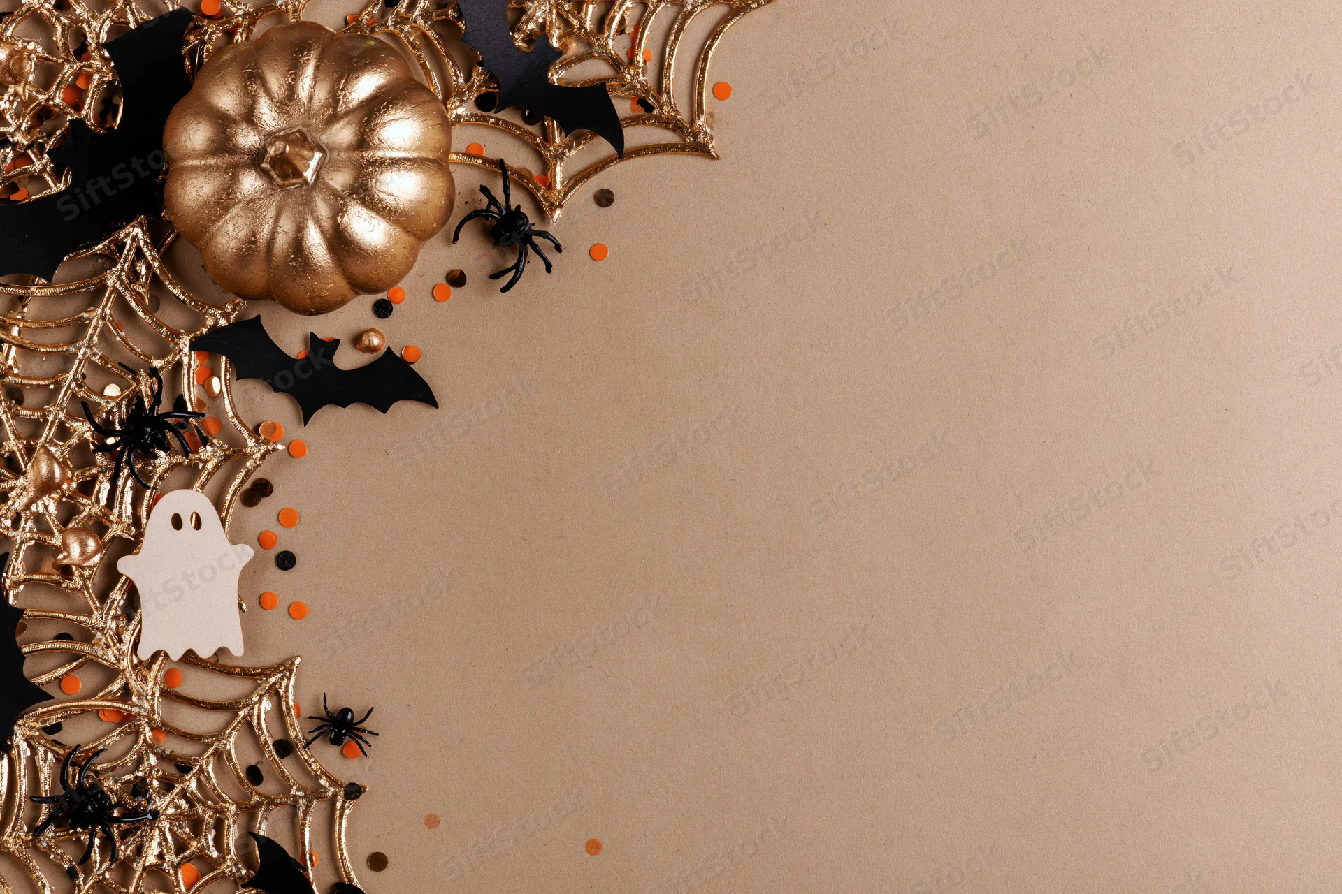 Halloween decorations arranged in flat lay on beige surface with copyspace