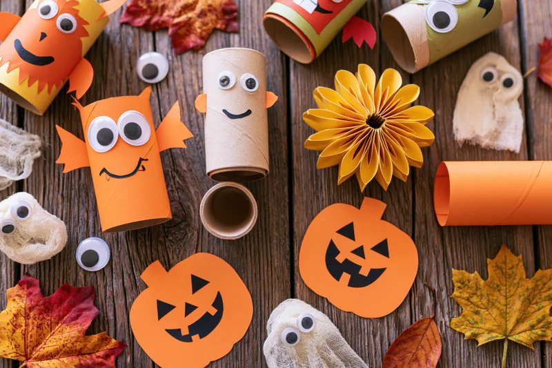 Halloween kids craft project flat lay on rustic wooden table with paper pumpkins ghosts and leaves