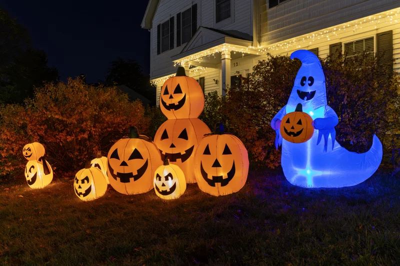 Inflatable halloween pumpkins and ghost glowing on front lawn at night