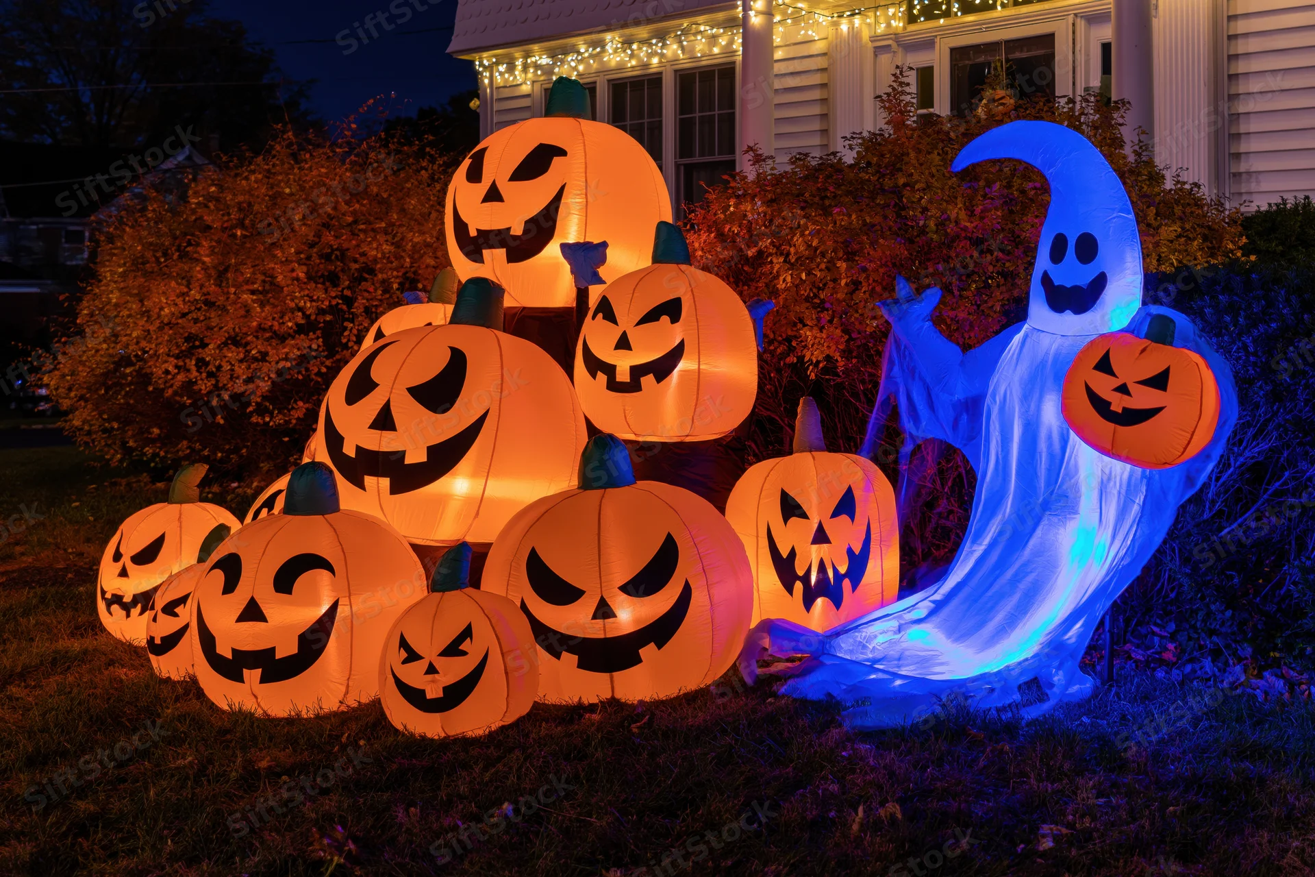 Inflatable halloween pumpkins and ghost glowing on a front lawn at night